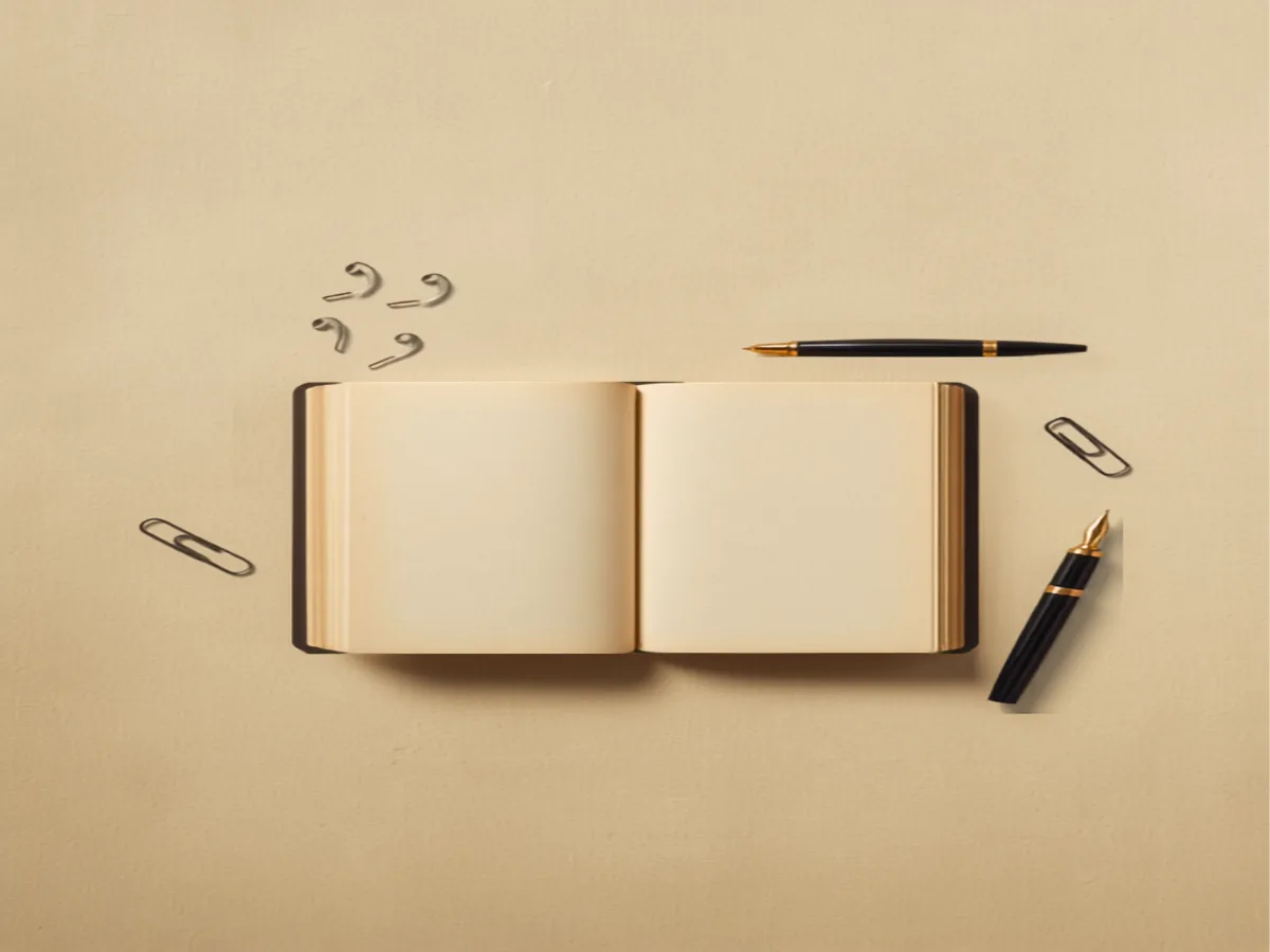 A scholar's desk with an open book, fountain pens and reference notes
